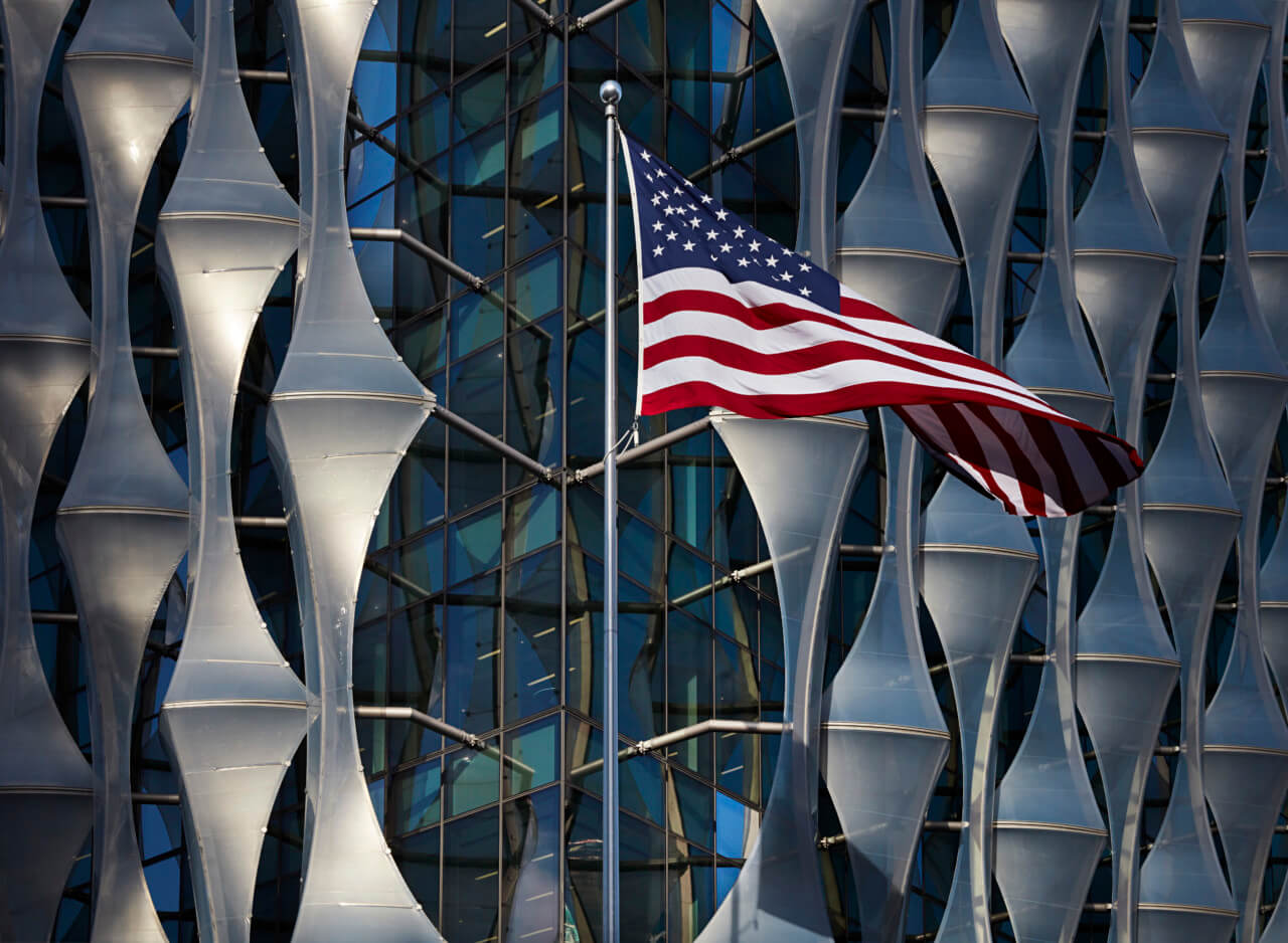Exterior of a US embassy facade with american flag