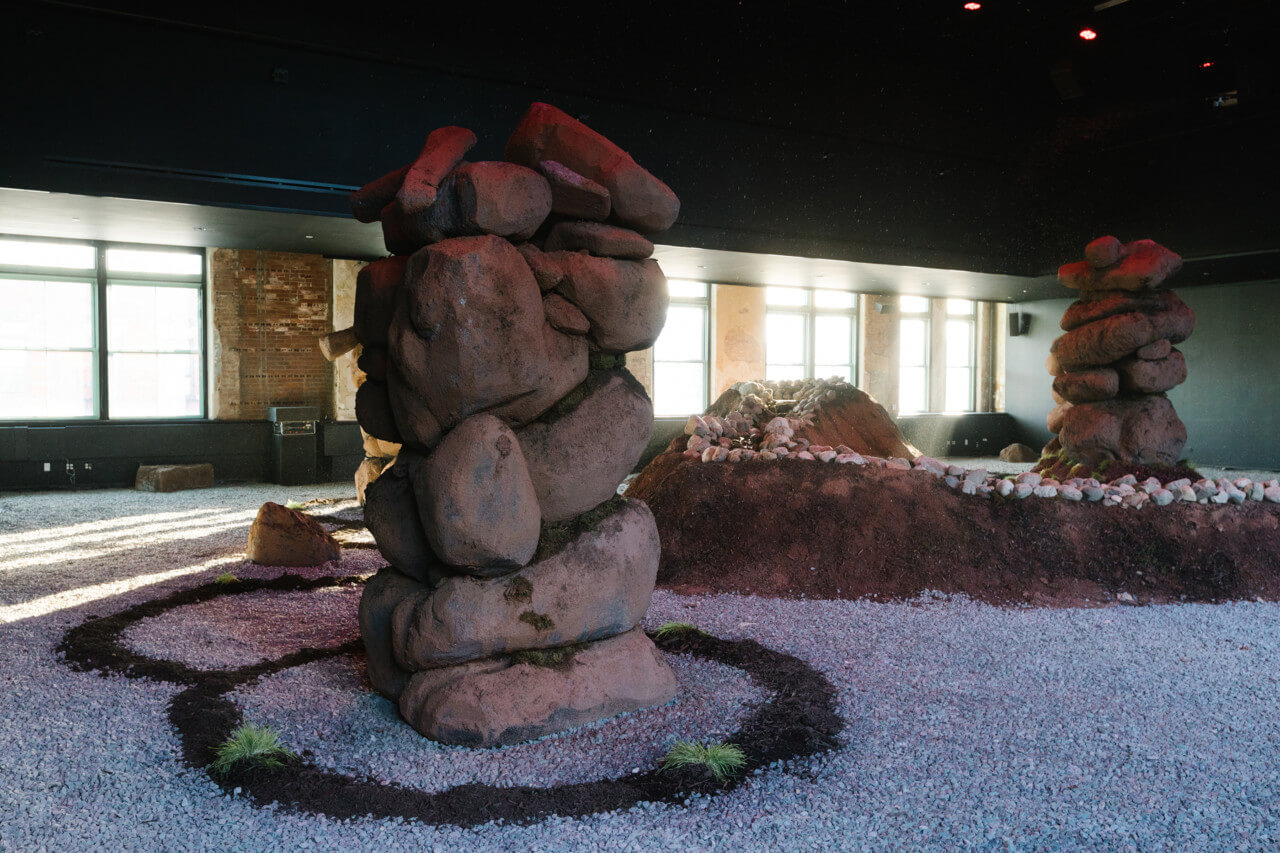 installation shot of performance space converted into a landscape with 3 stone pillars