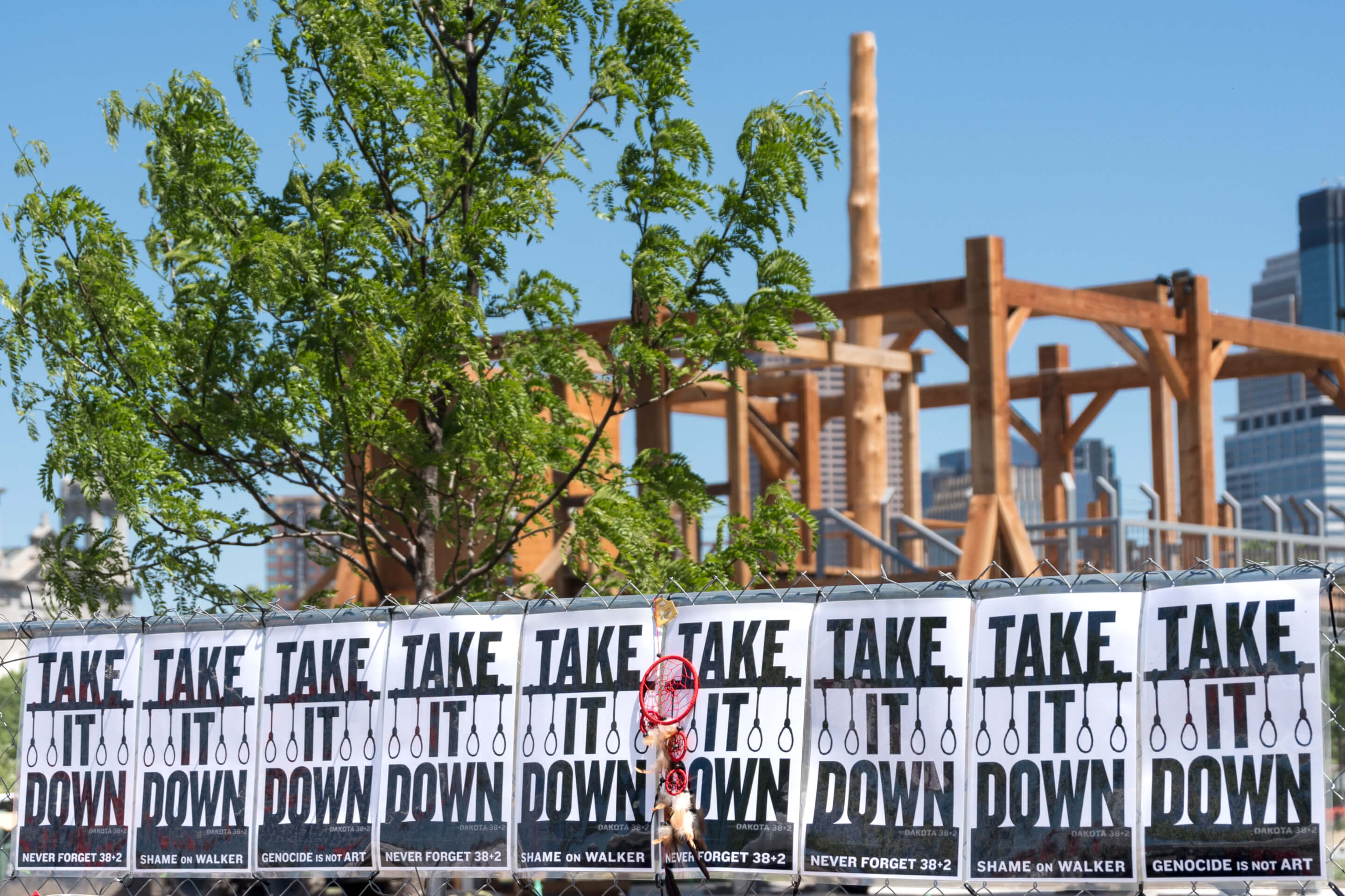 Scaffolding installation with TAKE IT DOWN signs and nooses strung along a fence
