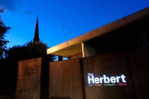 a darkened art museum at night with the spire of a cathedral in the background