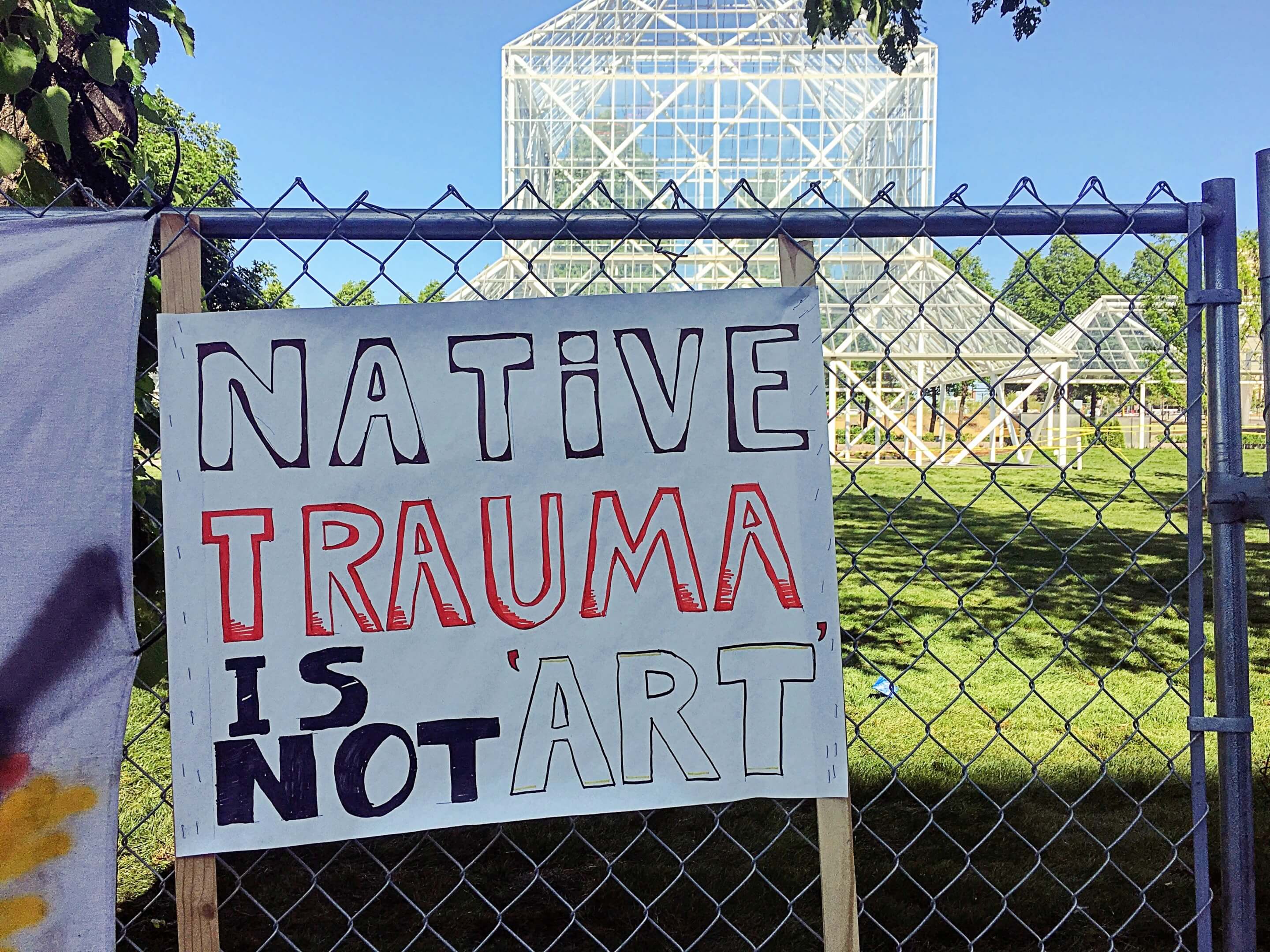 A protest sign in front of a scaffolding installation