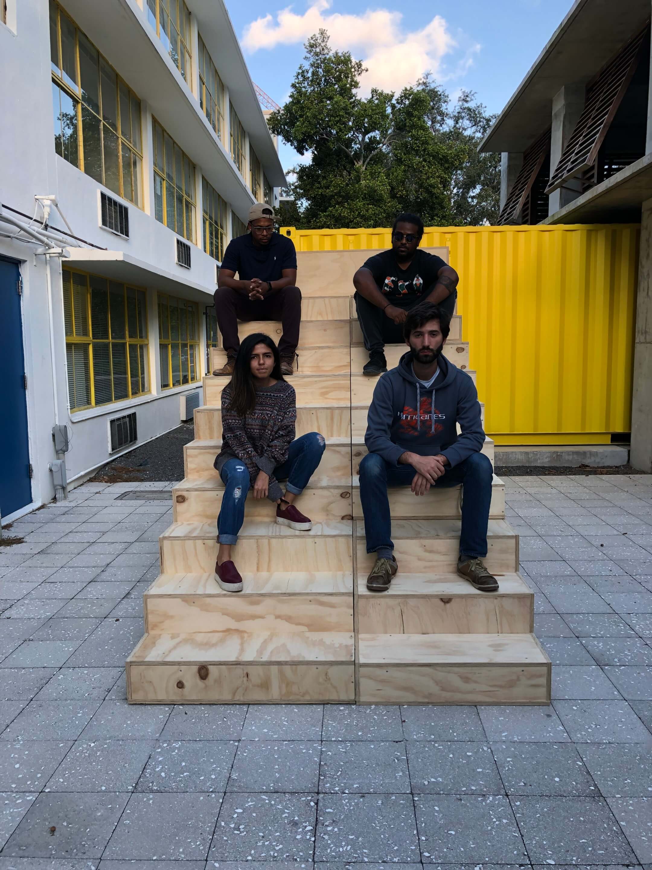 4 people sitting on pop-up plywood staircase