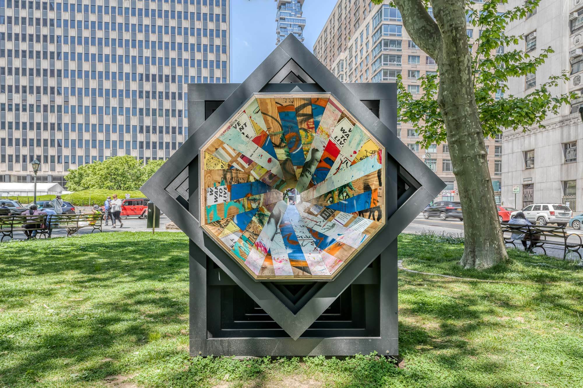 a colorful plywood art installation located in a grassy nyc park