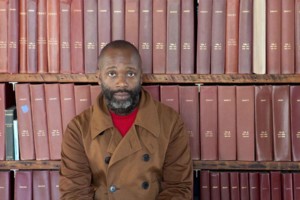 Image of an african american man, theaster gates, against book shelves