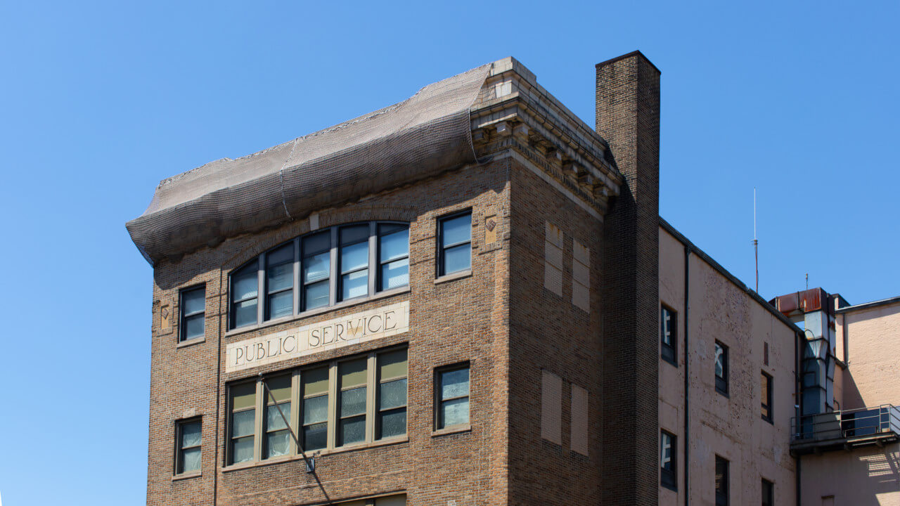 Detail of a long brick building with cornice wrapped