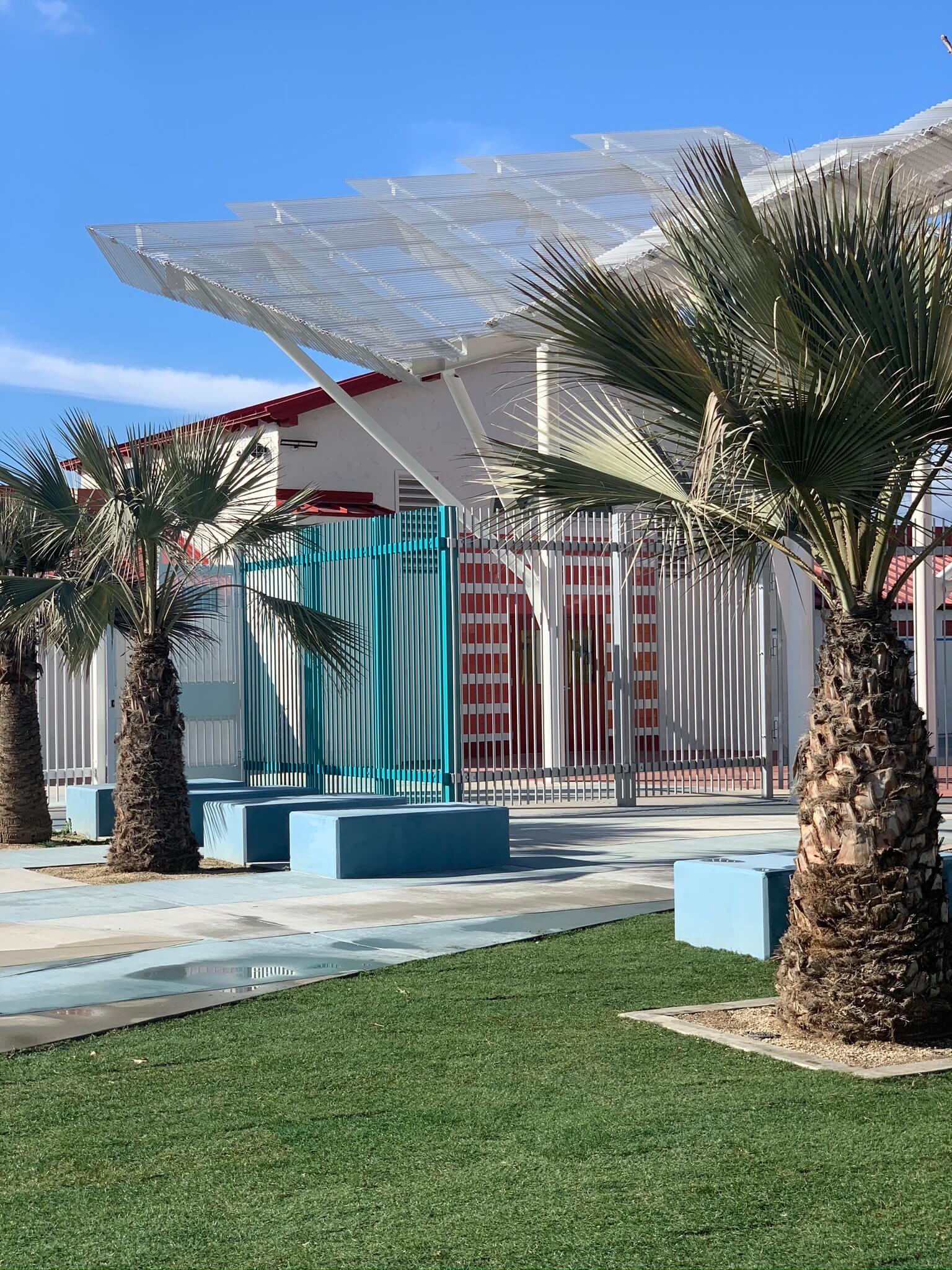 grass, palm trees, and a shade structure at a colorful recreational complex at the algin sutton pool