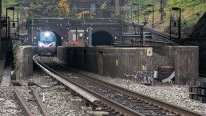 a train emerging from the gateway project tunnels surround by foliage