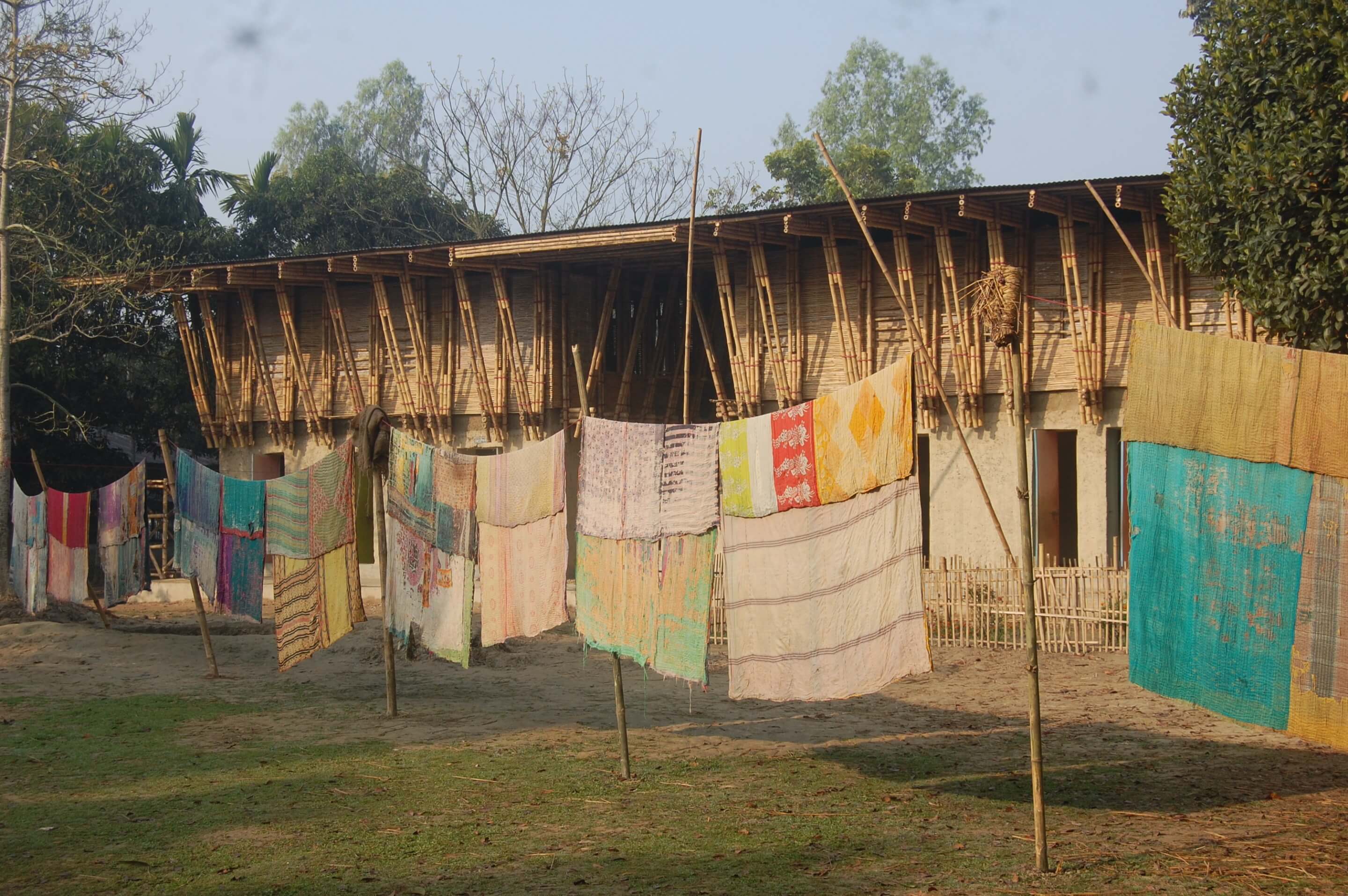 a rural school built from natural materials with tapestries hanging out front