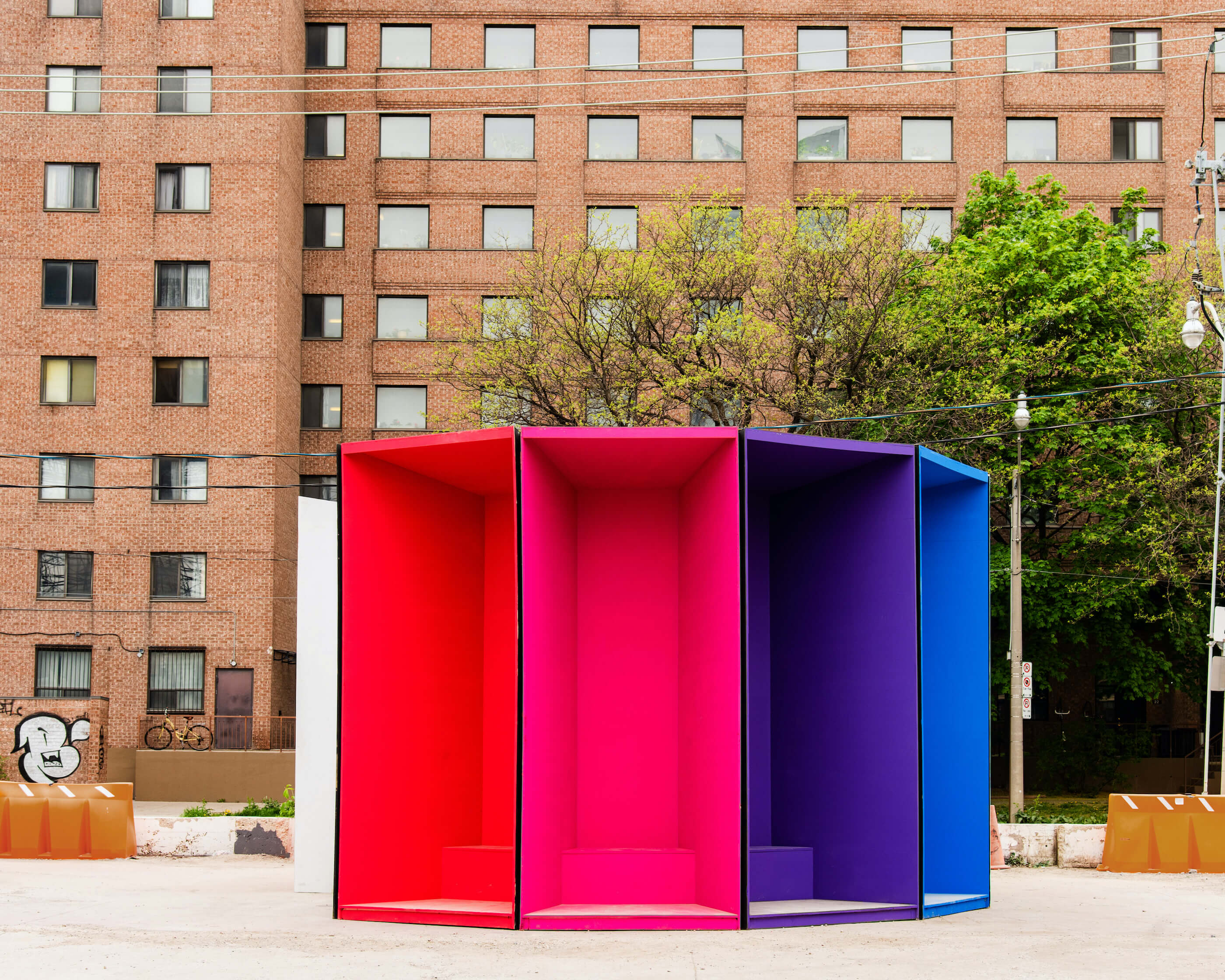 a colorful temporary pavilion with a brick apartment building in the background