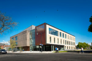 Exterior of the D’Youville Health Professions Hub, a bisected stone building with glass at the core
