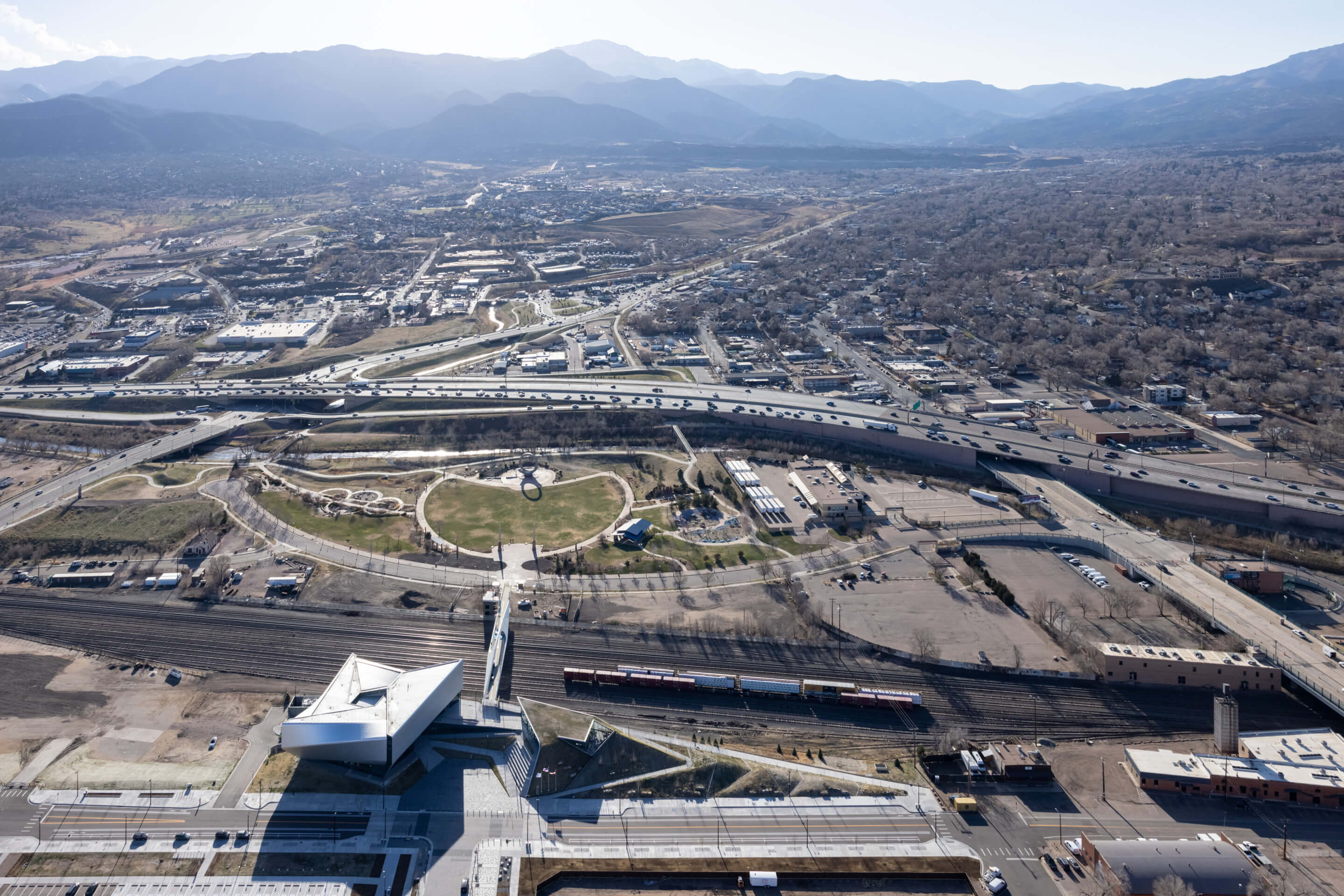 aerial view of a pedestrian bridge connecting a park with a museum with mountains in background