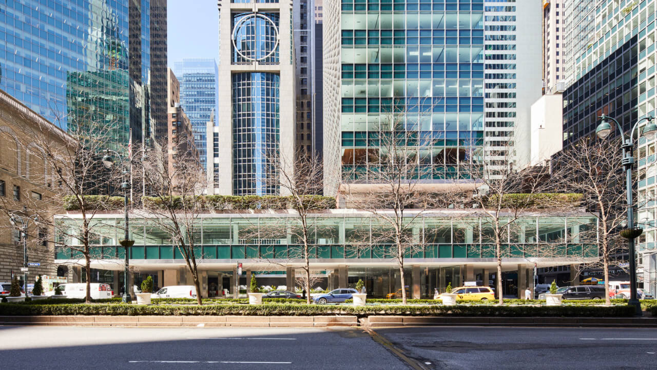 Exterior photo of a glassy modern venue floating over the street, lever house