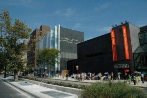 a new york city museum complex with people gathered outside as seen from the street, the bronx museum of the arts