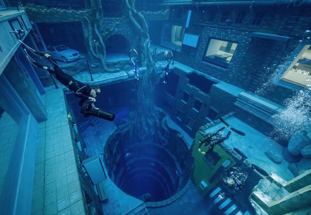 a diver descends into the fake ruins of an underwater city