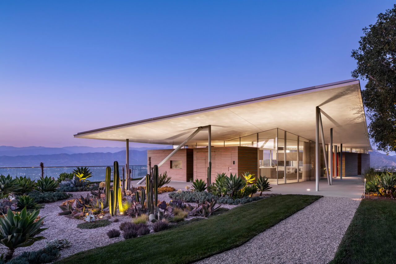 A large canopy covered glass home perched on a hill