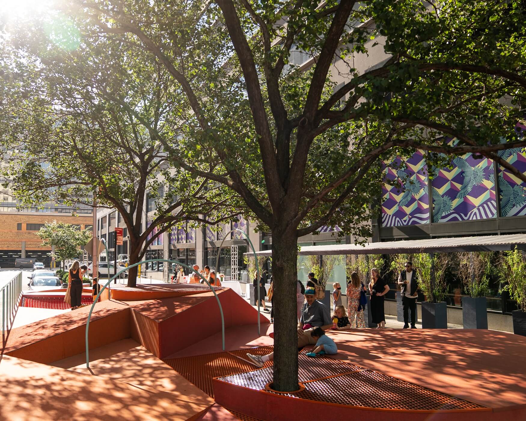 An orange metal installation outside with trees on it