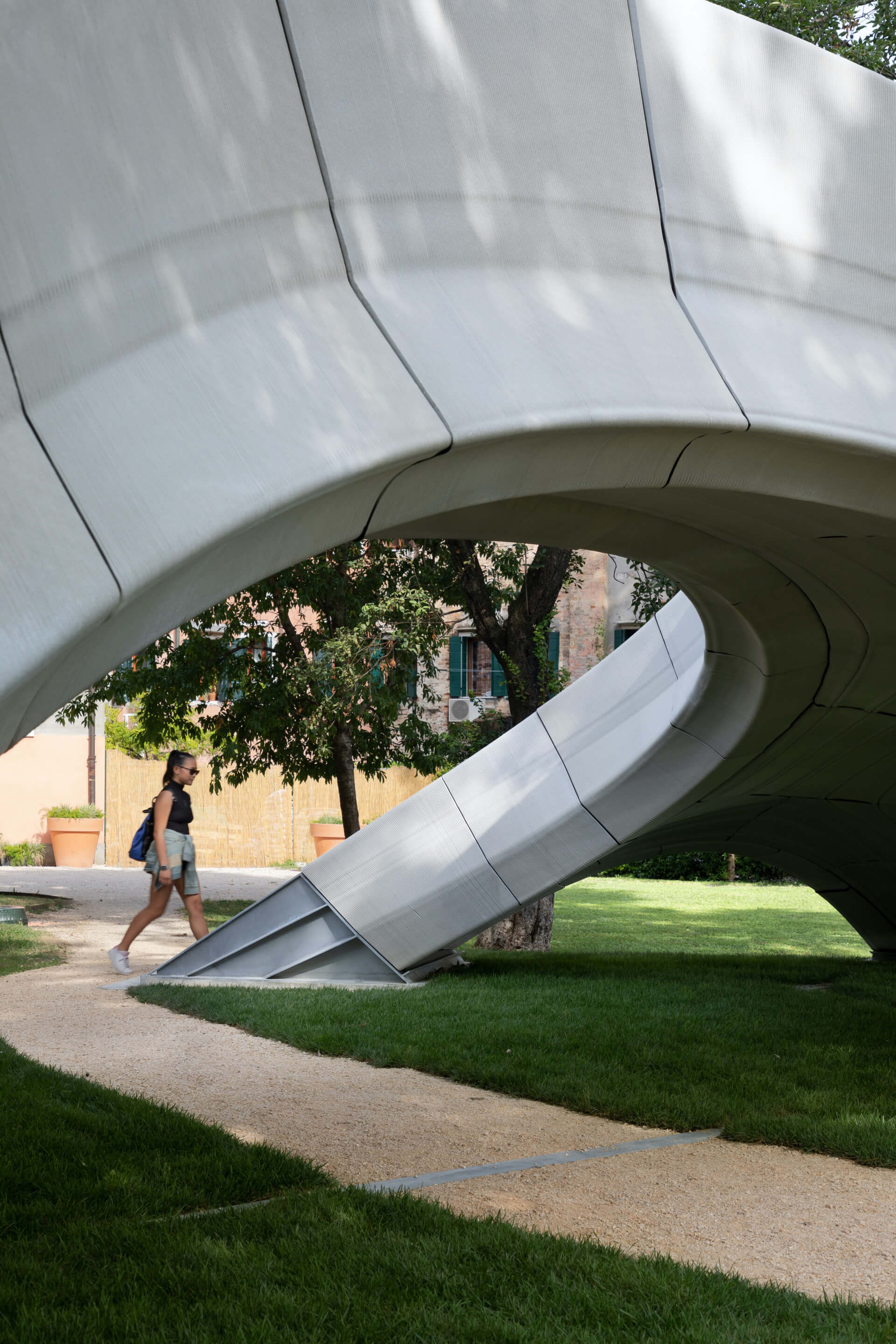 people explore a 3d-printed concrete arch footbridge located in a park