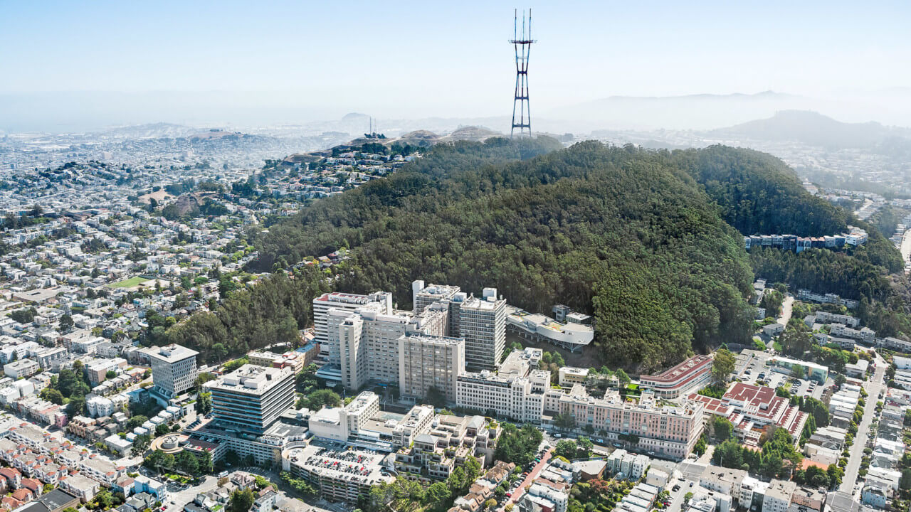 aerial view of a medical campus, the Parnassus Research and Academic Building, at the foot of a large hill in san Francisco