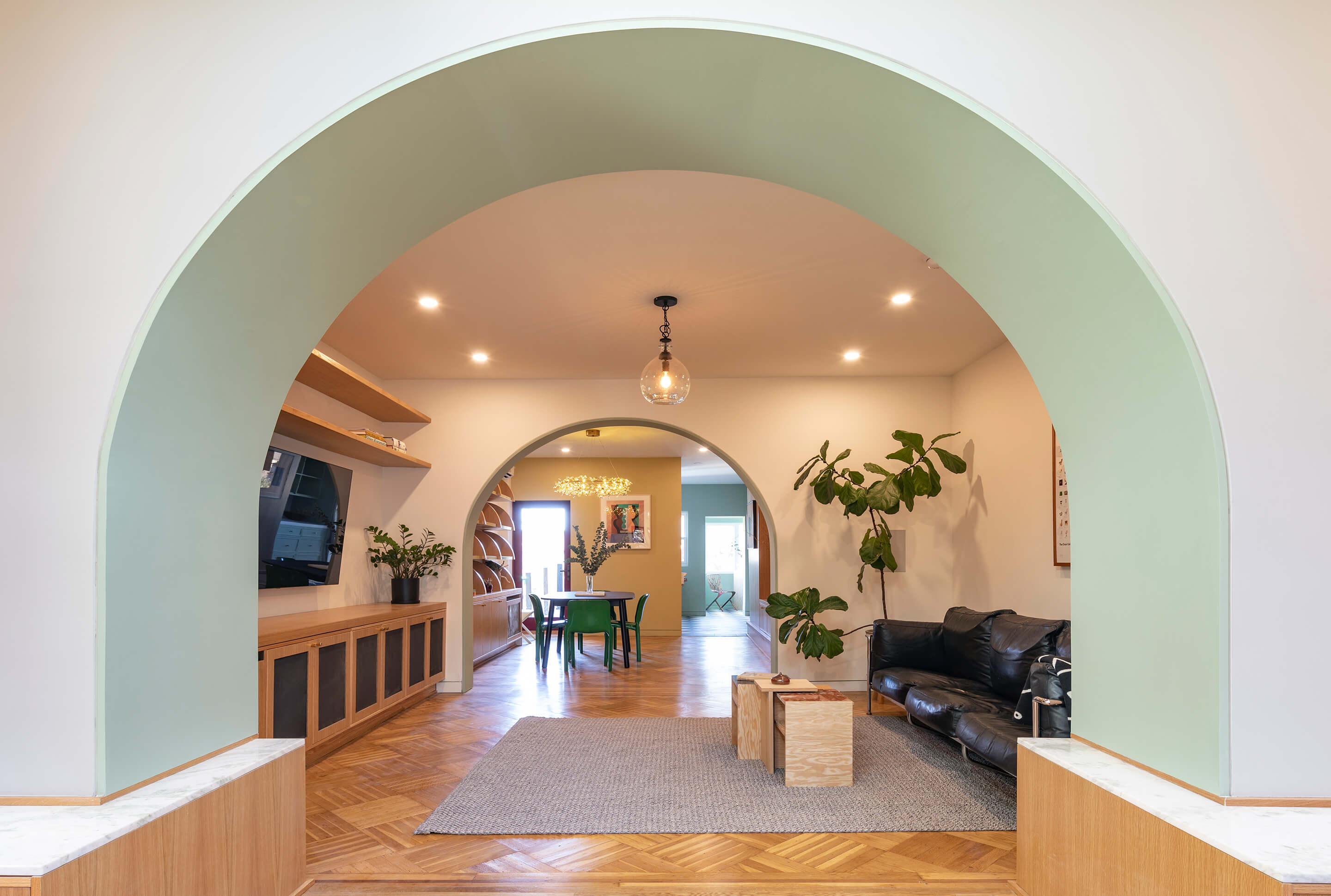 looking through mint green arches through a row home living room