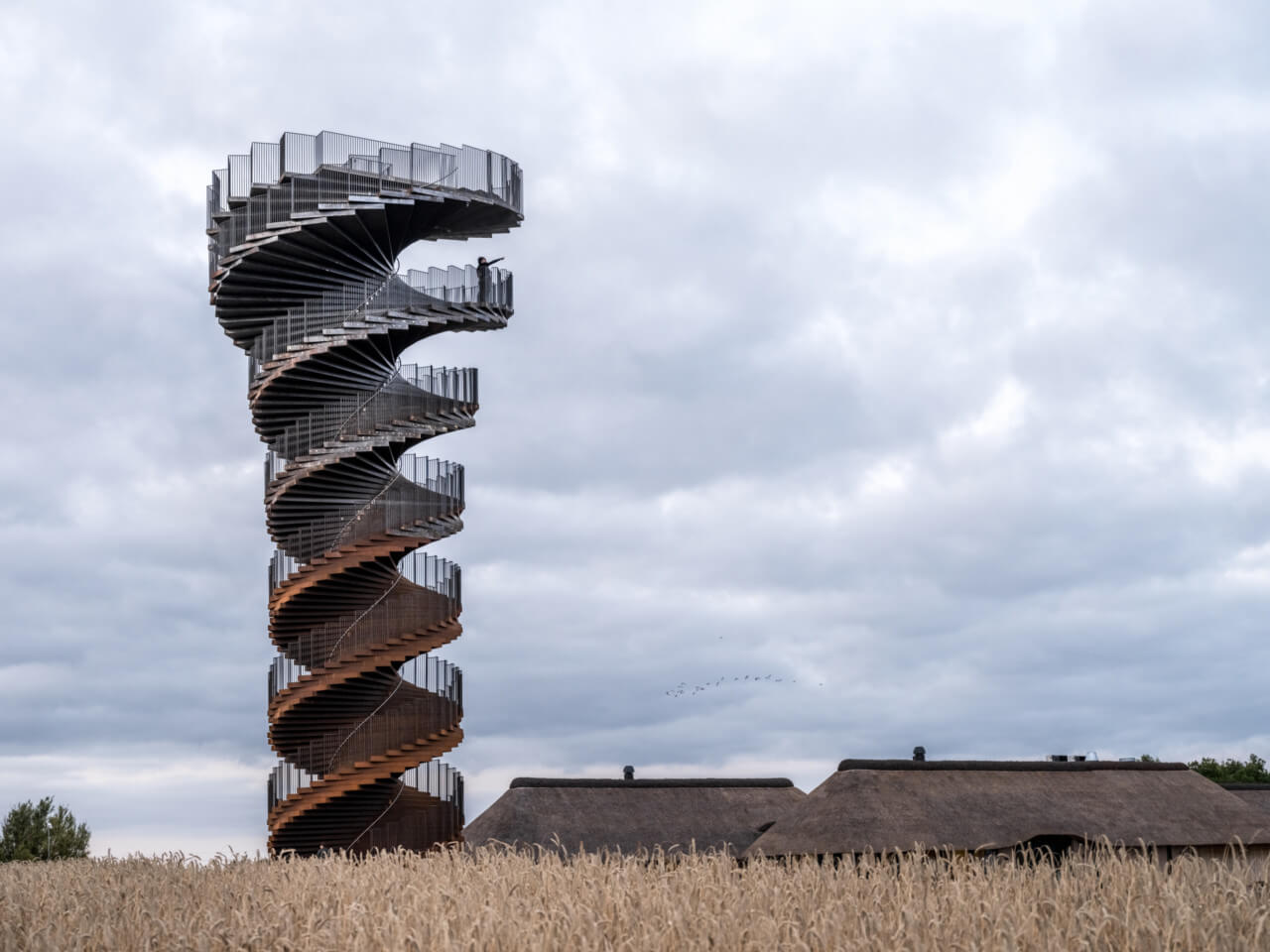 view of a spiraling observation tower surrounded by marshland and low buildings