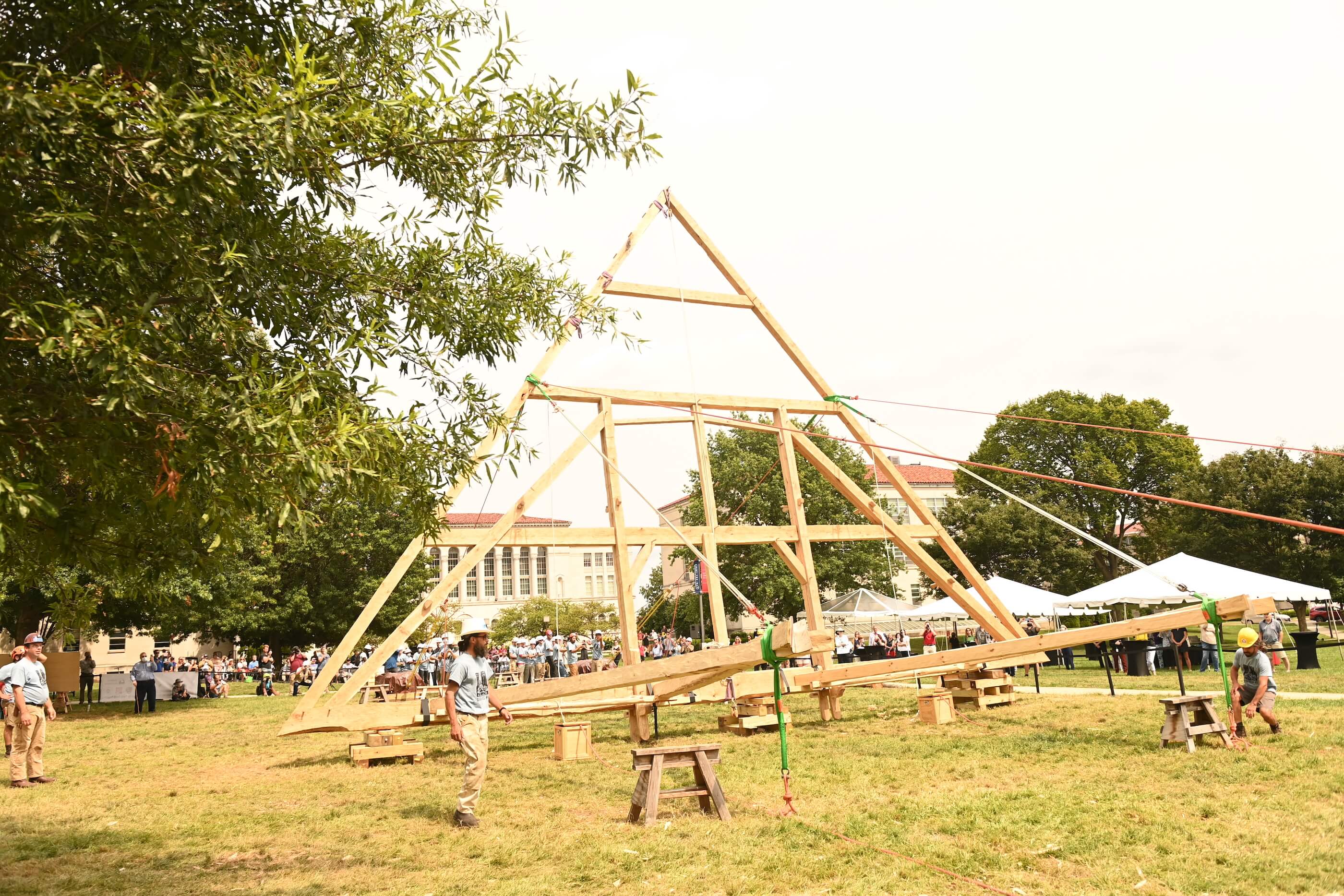 a construction team hand-raises a truss structure