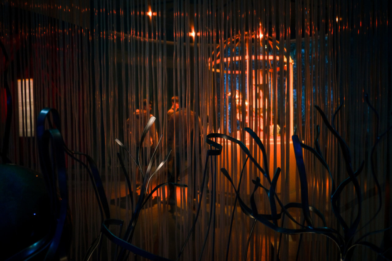 view of a dimly lit museum installation through a curtain