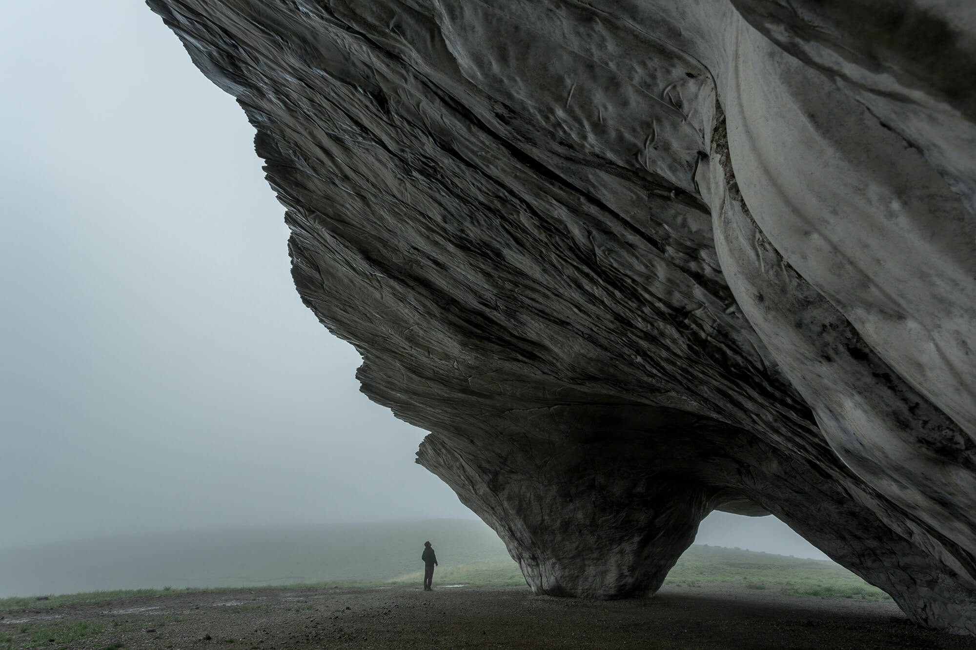 man staring up at a monolithic rock form