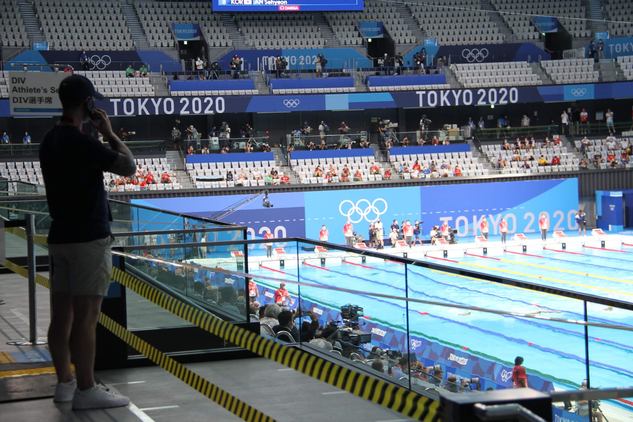 Swimmers in a big pool with tokyo olympics branding behind them