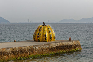 a pumpkin designed by yayoi kusama on a pier