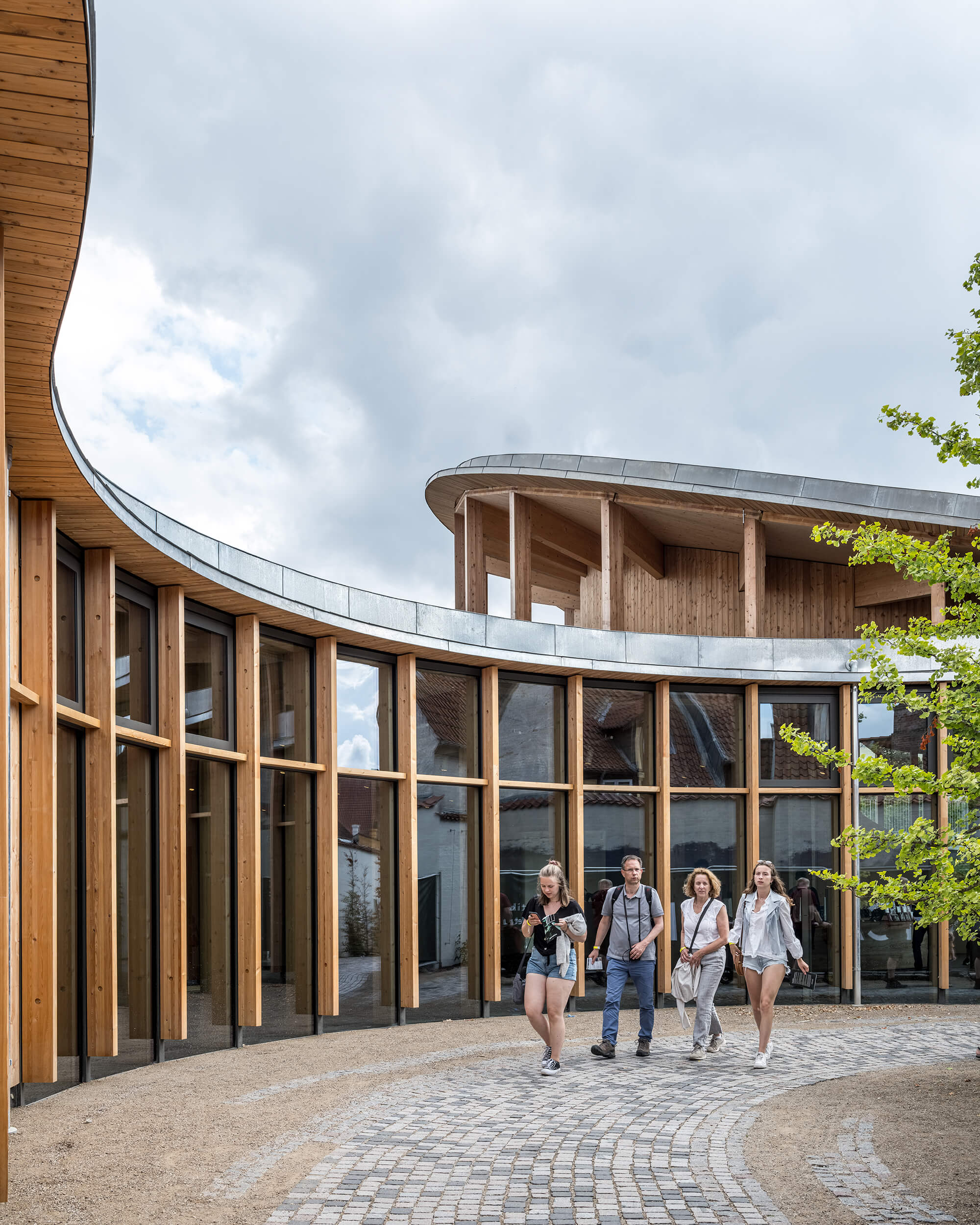 people walk around a curving timber and glass museum building dedicated to Hans Christian Andersen