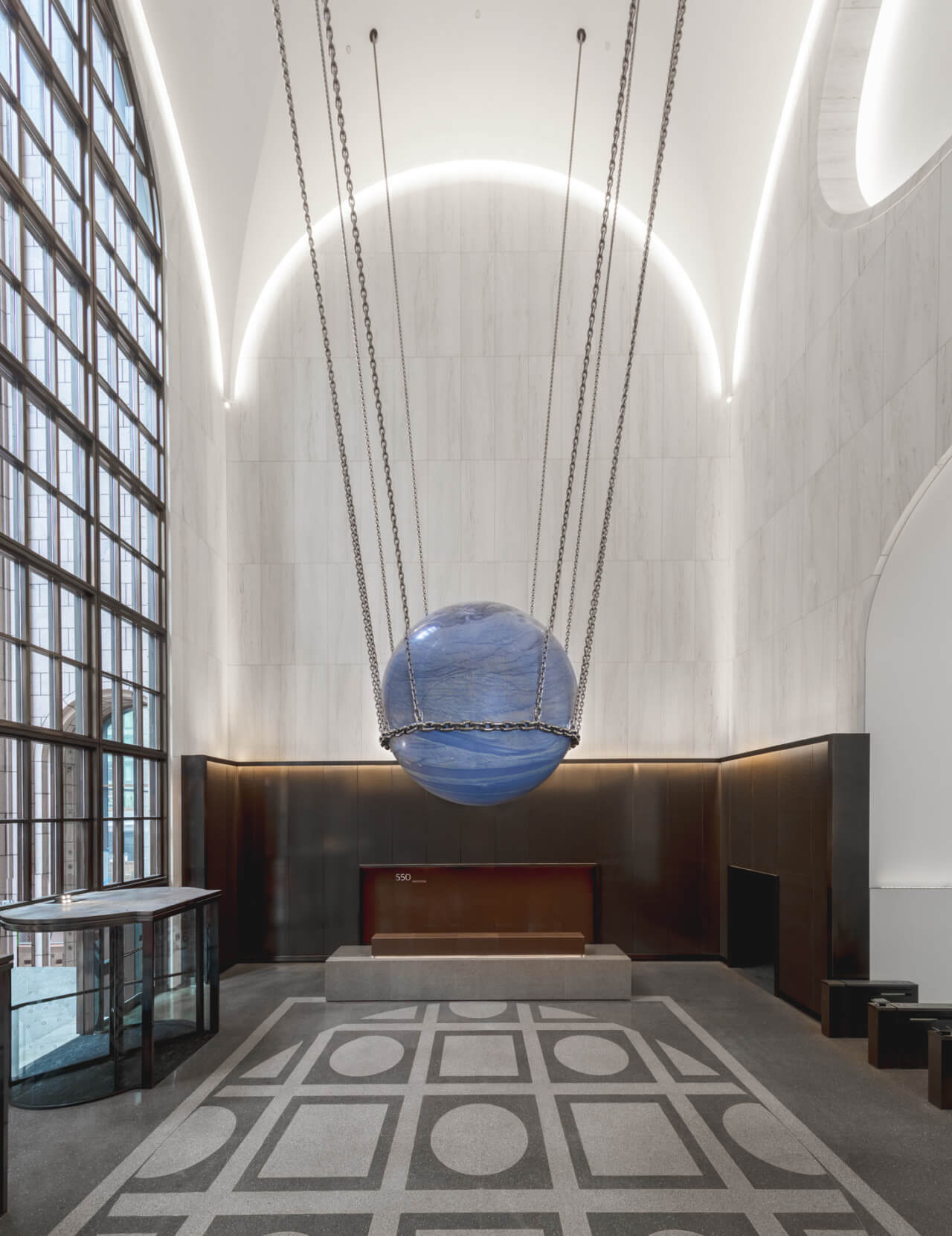 A blue sphere designed by alicja kwade hanging from the ceiling at 550 madison