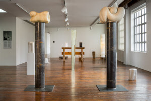 Interior photo of the useless architecture show at the noguchi museum showing sculptures wedged between two carved columns