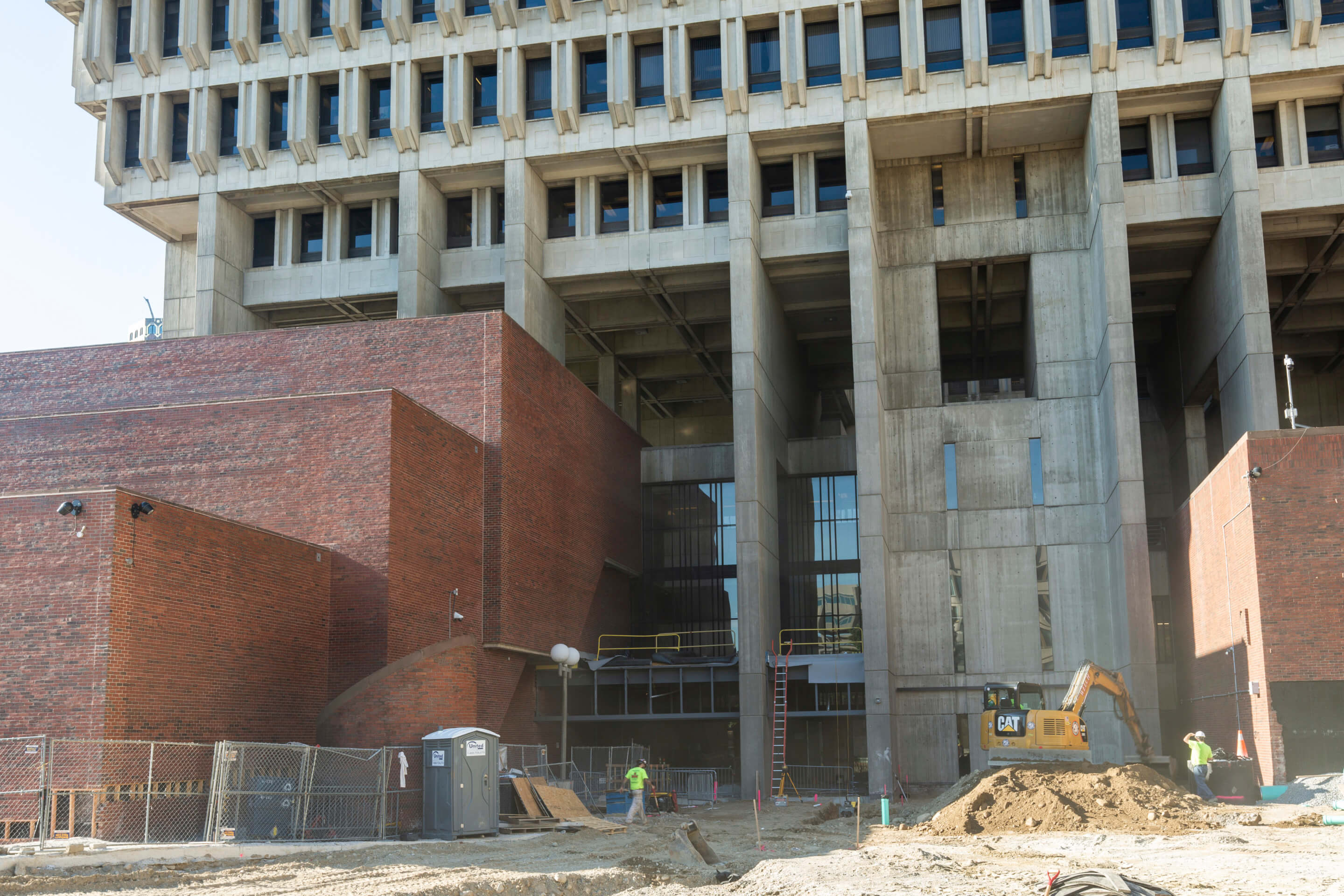 the towering entrance to boston city hall with a construction worker in front