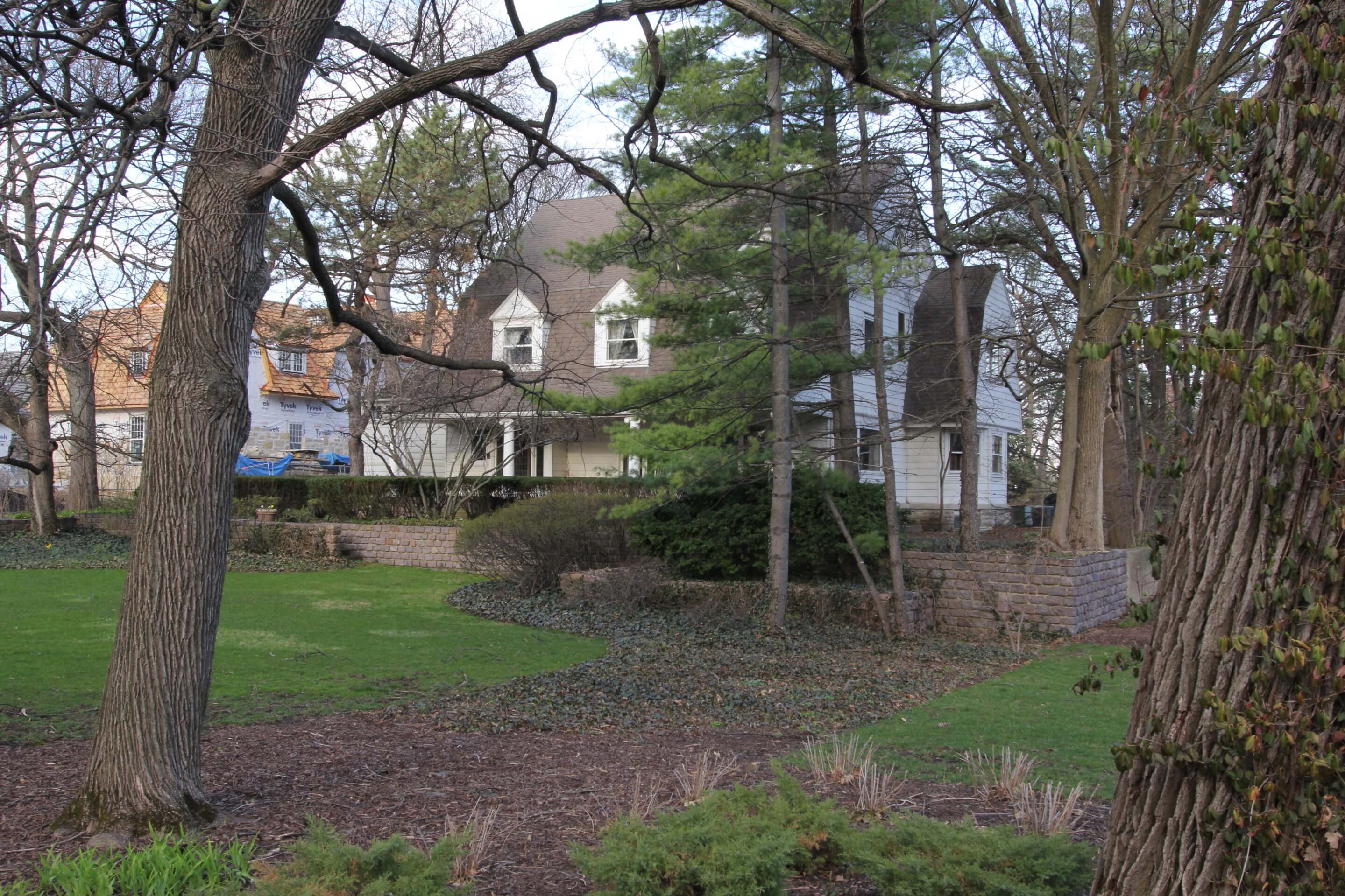 exterior view of a dutch colonial home through a stand of trees