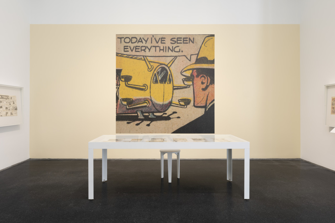 photograph depicting a museum gallery with a blown-up Dick Tracy comic strip on the wall