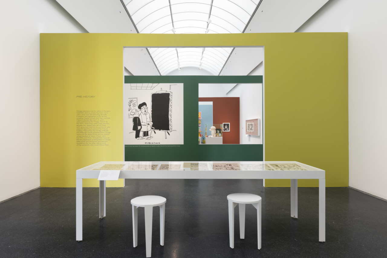 photograph depicting a museum gallery with partition walls painted yellow, green, red, and blue