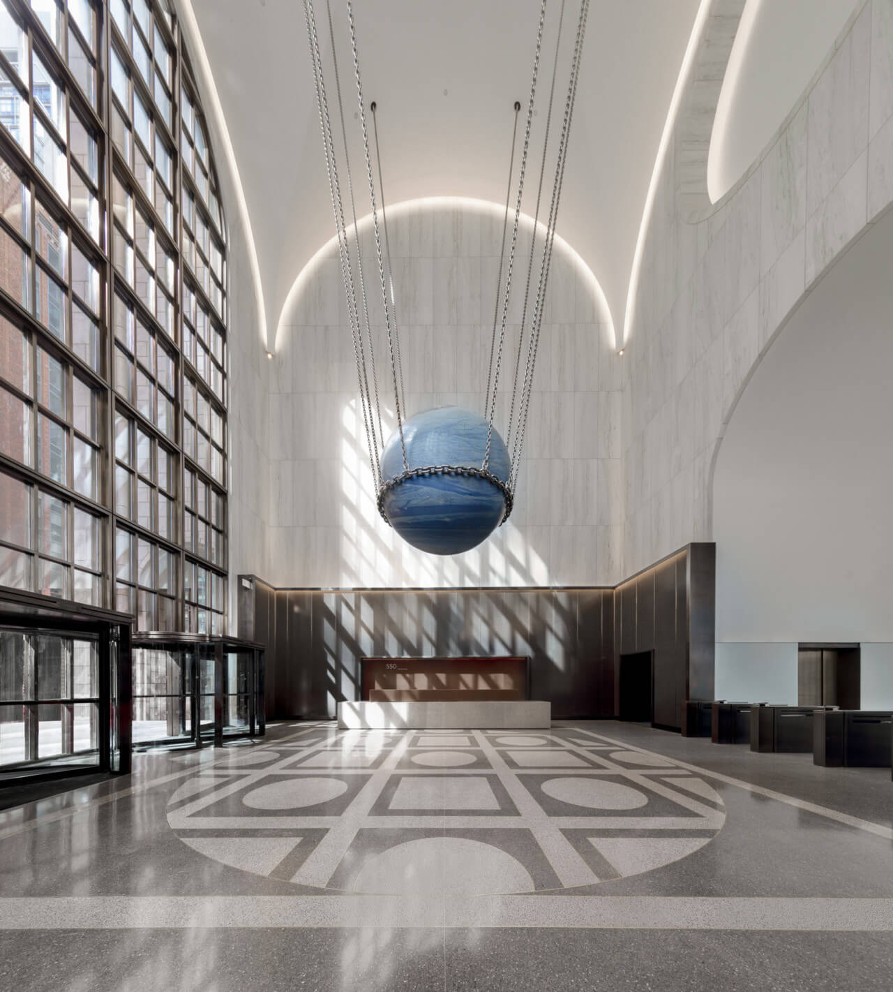 A blue sphere designed by alicja kwade hanging from the ceiling at 550 madison