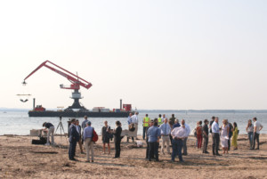 people gathered on a beach for an event with a crane in the background