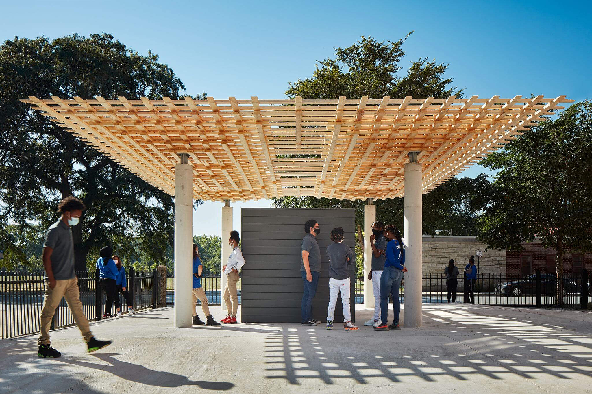 students congregate under a timber pavilion 