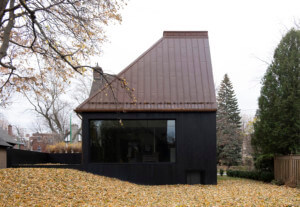 exterior of a home designed by atelier barda with a dark facade and sloping roof that abruptly cuts off