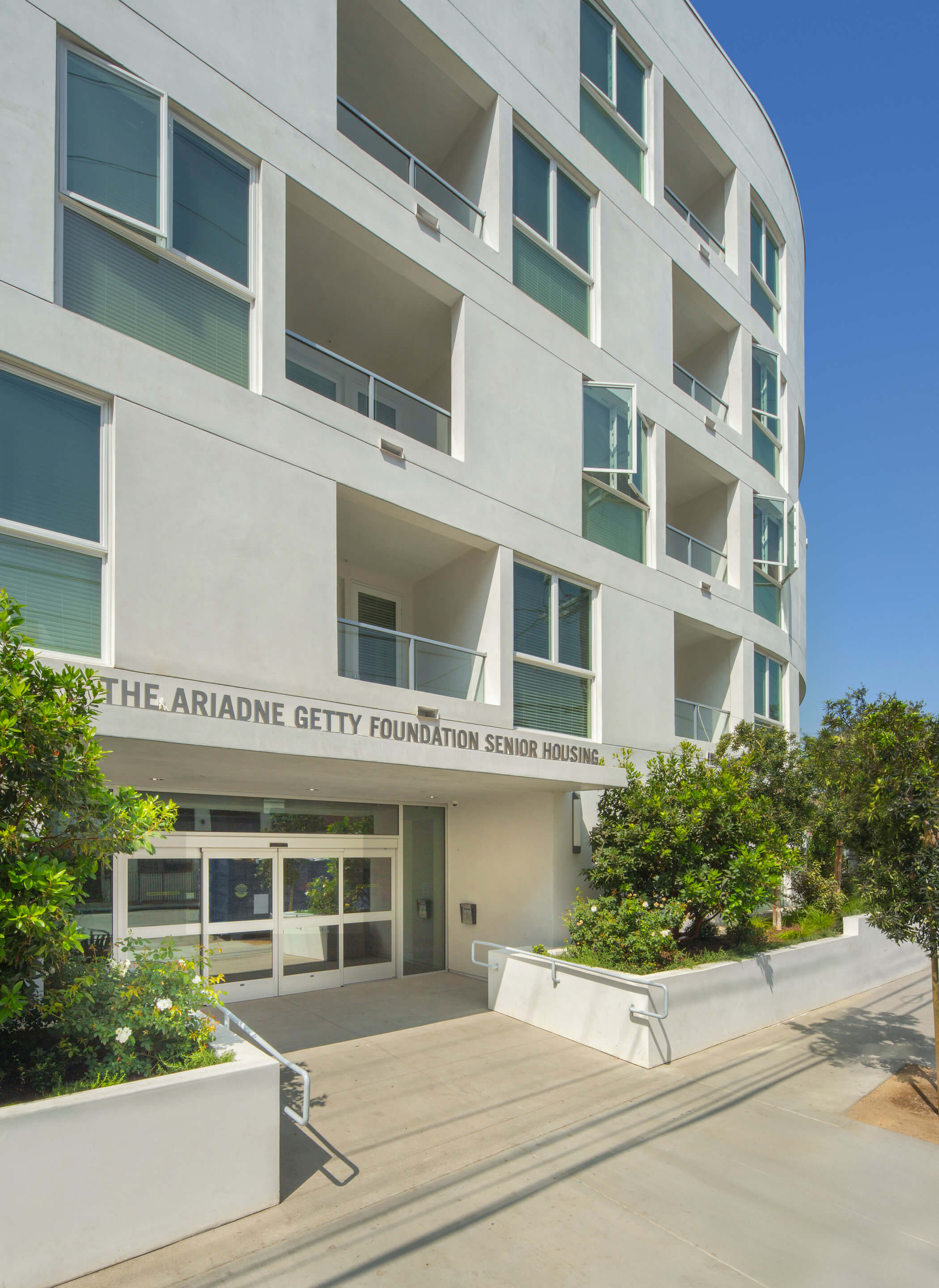 entrance to a white-stucco housing complex with a Ariadne Getty Foundation Senior Housing sign