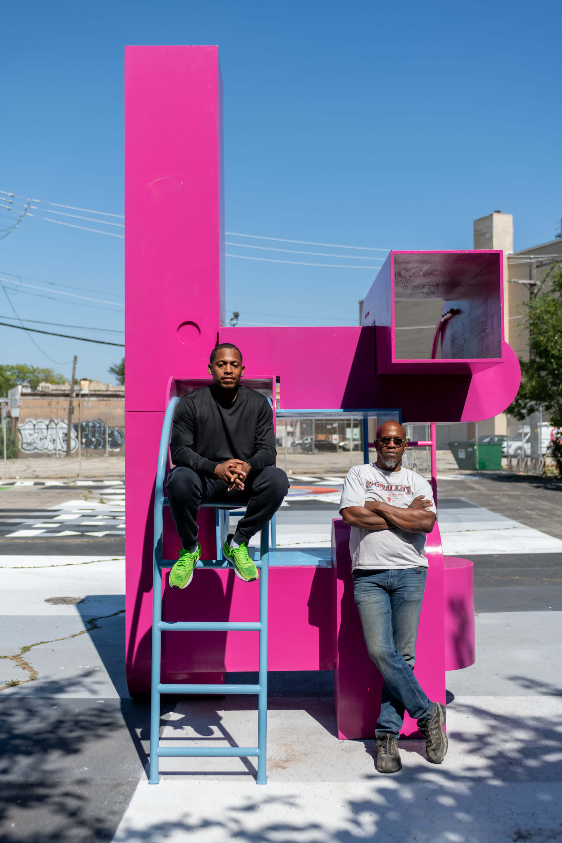 Two men on a giant magenta F