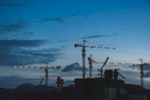 birds flock around construction cranes at dusk, a major source of carbon needing to be addressed at COP26