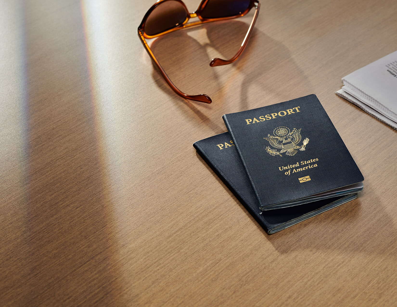 passports, sunglasses, and paper on a countertop