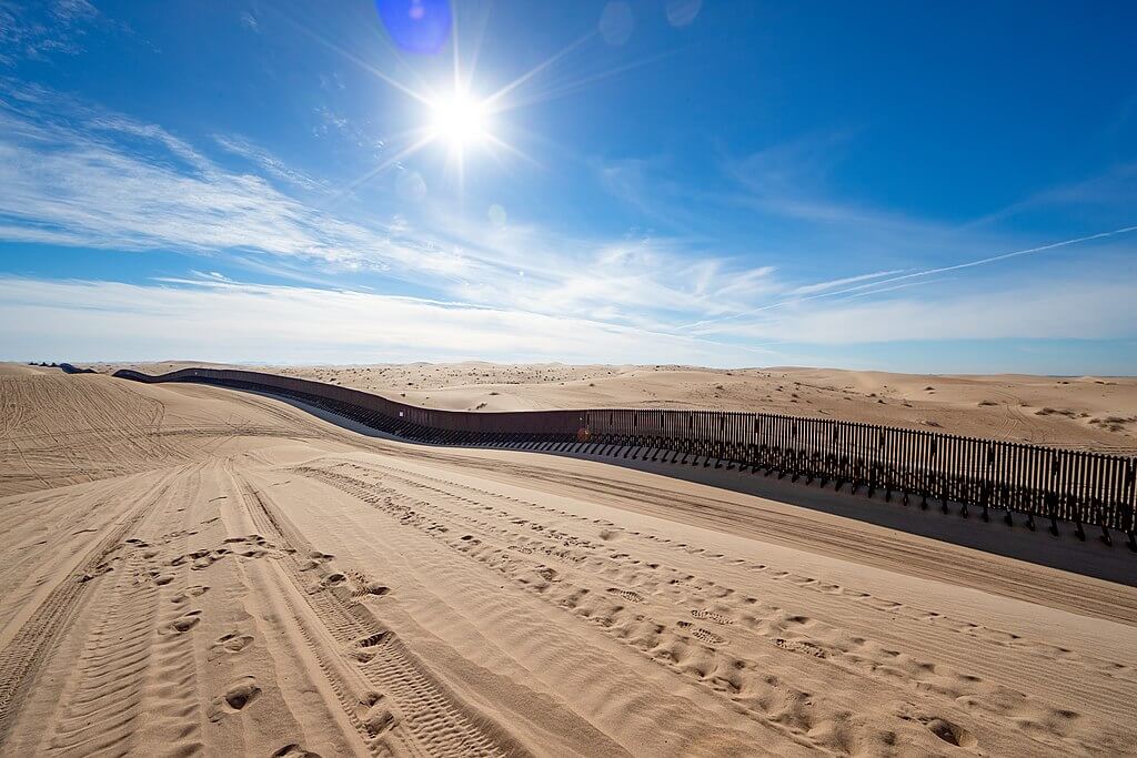 a border wall on top of sand dunes