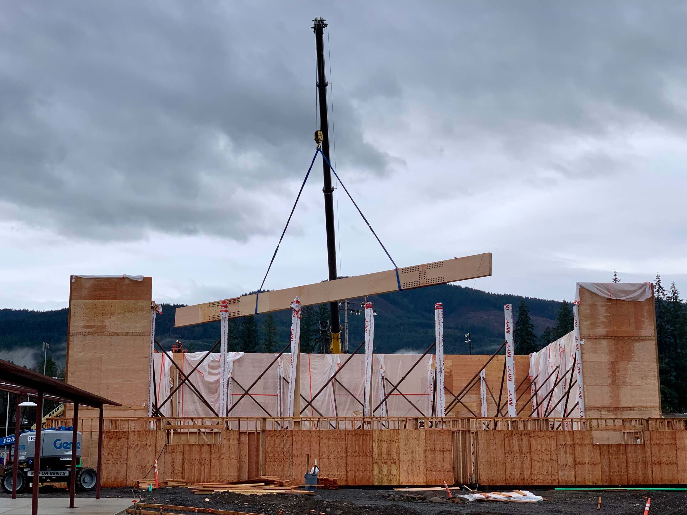a construction site with a long timber board being lifted into place