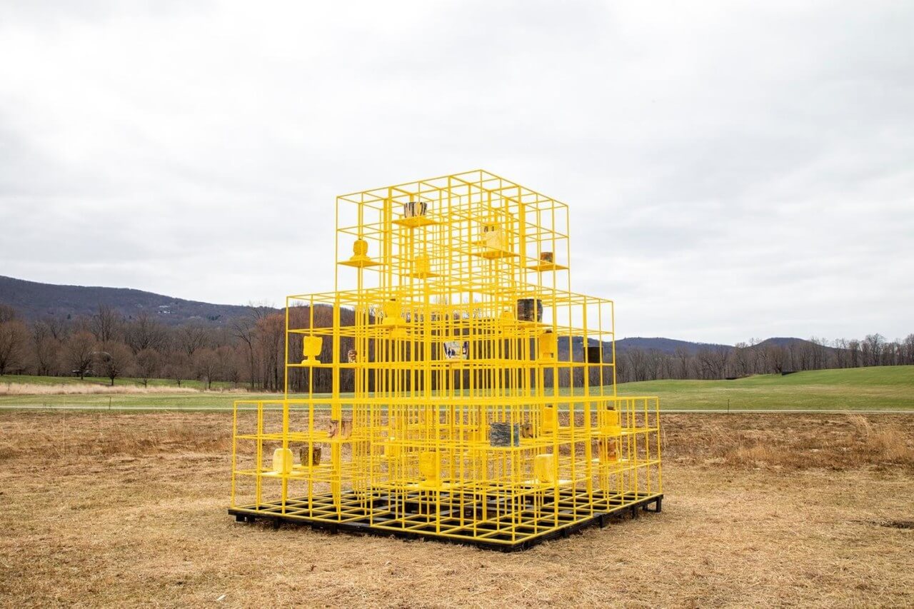 a yellow cage installation in an open field, an outdoor art piece