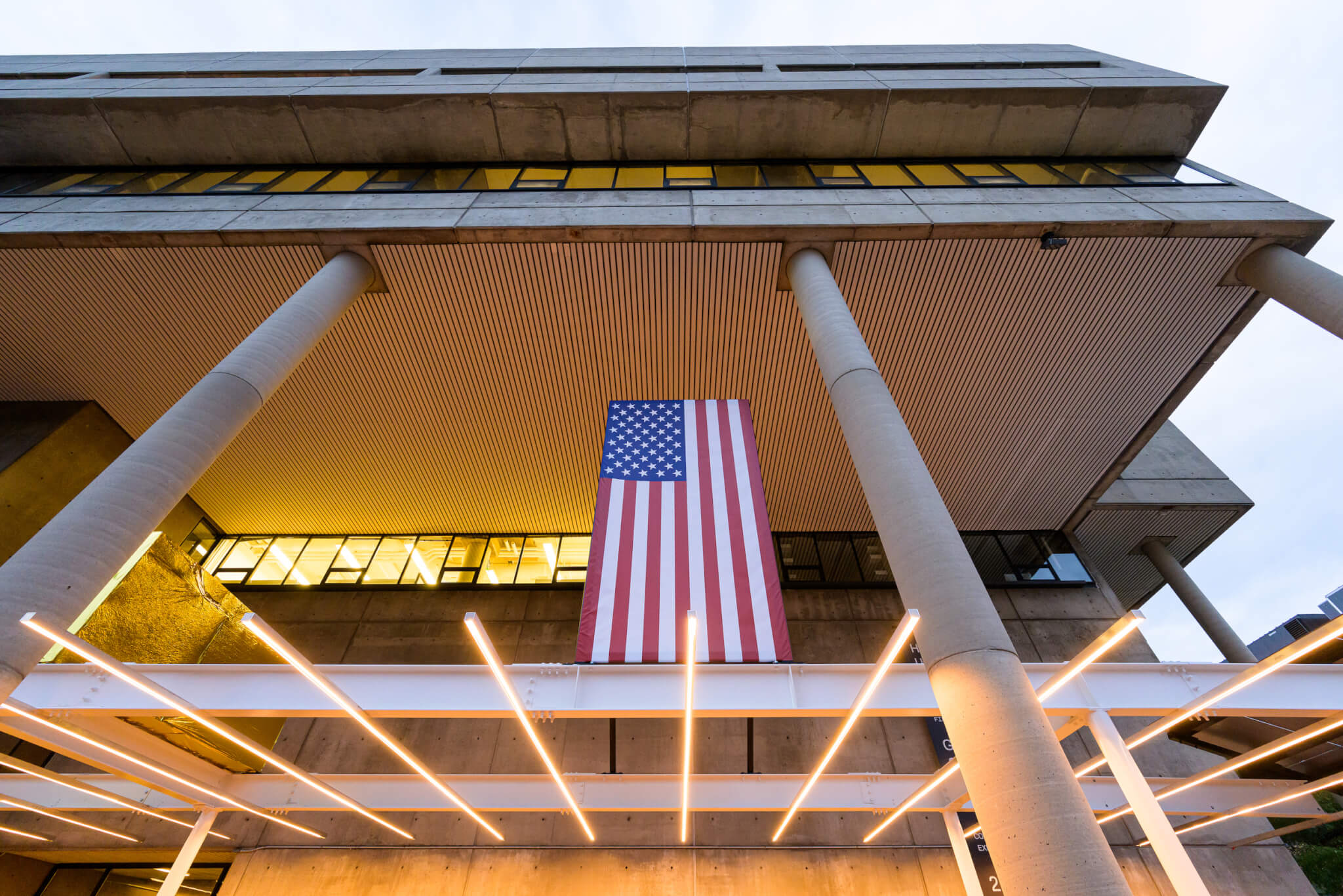 an array of LED lights and american flag above an outdoor plaza at an academic building