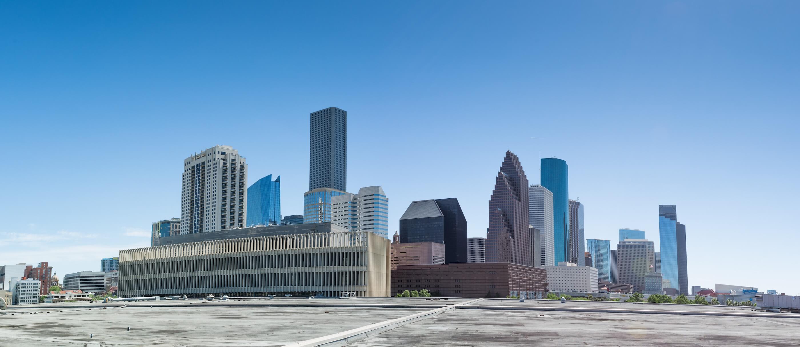 view of a modernist building surrounded by parking lots with the downtown houston skyline in the background