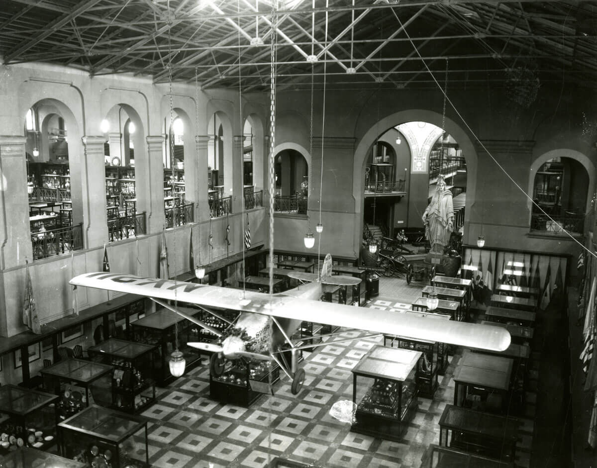 b&w photo of an airplane suspended in a museum